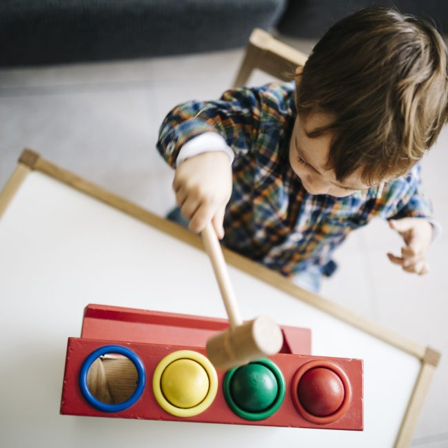 Little boy playing with wooden motor skill toy